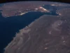 How the world absorbed the Hormuz oil shock Night view from orbit of the Gulf of Oman and the Strait of Hormuz, with city lights along the coasts and the curve of the Earth on the horizon