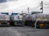 The arithmetic of a ration cut A line of flatbed trucks loaded with aid pallets parked at a desert crossing point.