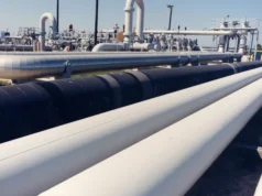 Lo que pueden y no pueden hacer las reservas de emergencia de petróleo Large white crude oil pipelines running in parallel across a storage site under a clear sky, with valves and a pump station behind.